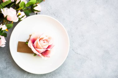 Beyaz tabak ve gül çiçekli bahar sofrası. Yıldönümü ya da düğün için masa dekorasyonu. Üst görünüm beyaz.