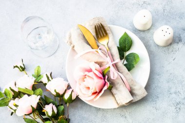 Beyaz tabak ve gül çiçekli bahar masası. Yıldönümü ya da düğün için masa dekorasyonu. Beyazla yatıyordu.