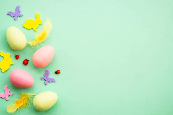 stock image Happy Easter background. Eggs, rabbit, spring flowers and butterfly. Flat lay image at green background.