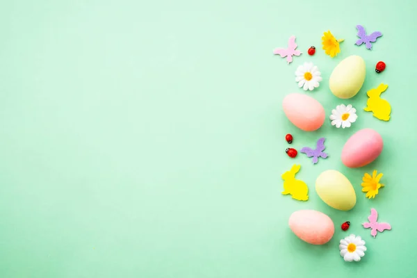 stock image Easter background. Eggs, rabbit, spring flowers and butterfly. Flat lay mock up at green background.