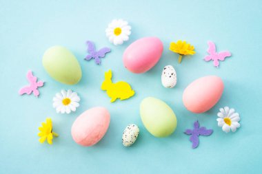 Mavinin Paskalya arkaplanı. Yumurta, tavşan, bahar çiçekleri ve kelebekler. Düz yatıyordu.