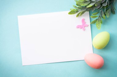 Paskalya arkaplanı ya da mavi kart. Yumurtalar, bahar yaprakları ve kelebek. Kopyalama alanı olan düz.