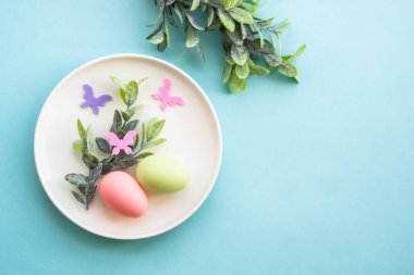 Paskalya sofrası, yumurta ve yeşil dallı beyaz tabak. Kopyalama alanı olan üst görünüm.
