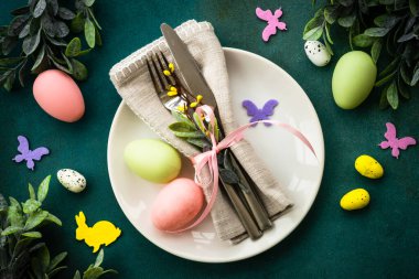 Easter table setting, Easter food background. White plate with cutlery, eggs, spring flowers and butterfly. Flat lay. clipart