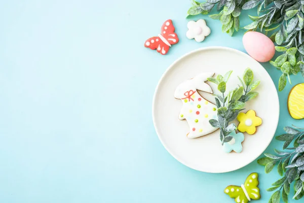 Easter food background. White plate with eggs, spring flowers and easter cookies. Flat lay.