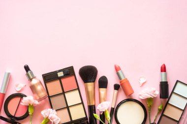 Makeup professional cosmetic products on pink with flowers. Flat lay image with copy space.