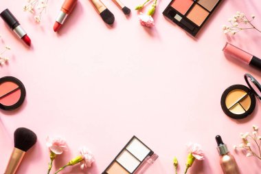 Makeup professional cosmetics on pink background with flowers. Flat lay with copy space.