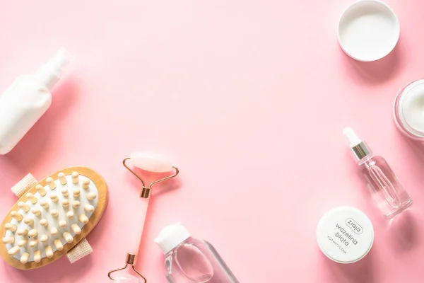 stock image Natural cosmetics on pink. Skin care product, cream, soap serum, jade roller and white towel. Flat lay image with copy space.