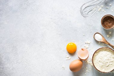 Flour, sugar, eggs and rolling pin at light stone table. Top view with copy space.