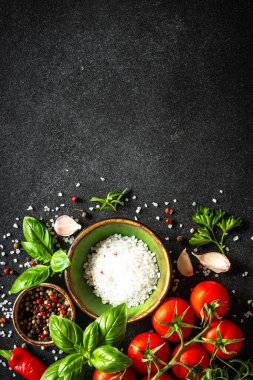 Sebzeler, otlar ve baharatlarla dolu siyah taş masada yemek. Kopyalama alanı olan üst görünüm.