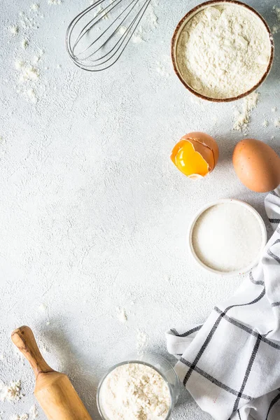 stock image Baking background at light stone table. Flour, sugar, eggs and rolling pin. Top view with copy space.