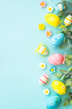 Paskalya arkaplanı ya da mavi kart. Yumurtalar, bahar yaprakları, çiçekler ve renkli kelebekler. Kopyalama alanı olan düz.