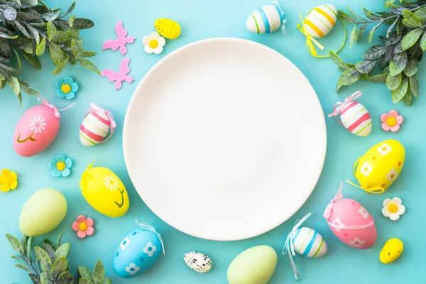 Easter table setting, Easter food background. White plate with eggs, flowers and green leaves. Flat lay.