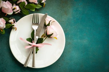 Bahar masası. Çatal bıçaklı ve çiçekli beyaz tabak. Kopyalama alanı olan üst görünüm.