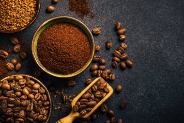 Roasted coffee beans, ground coffee and instant coffee in bowls at dark background. Top view image.