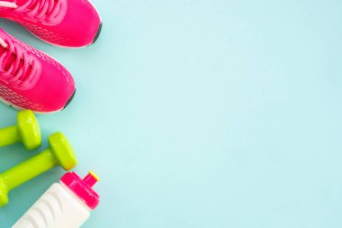 Dumbbells, sneakers, measuring tape, water bottle and notepad on blue. Healthy lifestile, fitness flat lay.