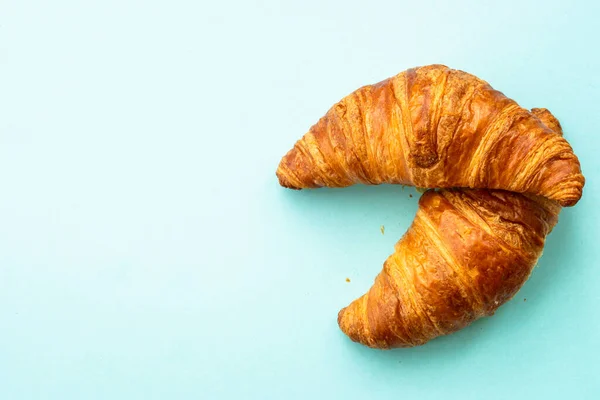 Croissant at blue background. French bakery. Flat lay image with copy space.