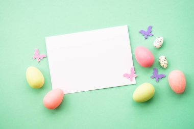 Mutlu Paskalyalar. Yumurta, tavşan, bahar çiçekleri ve kelebek. Yeşil arkaplanda düz resim yatıyordu.