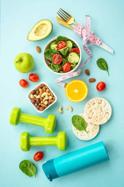 Diet food, healthy lifestyle and fitness background. Vegan salad, crispbread, fruits and dumbell. Flat lay image.