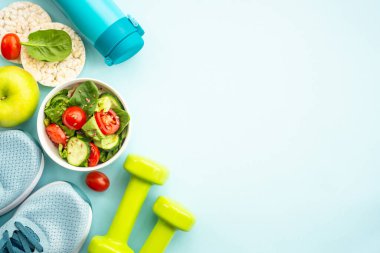 Sağlıklı yaşam tarzı ve diyet gıda geçmişi. Spor ayakkabılar, dambıl ve mavi üzerine sağlıklı yiyecekler. Kopyalama alanı olan düz.