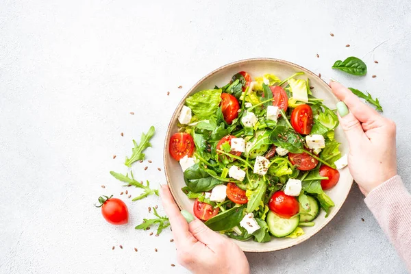 Stock image Spring salad in craft plate. Spinach, arugula, tomatoes and feta with olive oil. Top view on white.