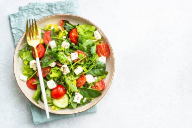 El sanatları tabağında bahar salatası. Ispanak, roka, domates ve zeytinyağlı feta. Beyaz üzerine üst görünüm.