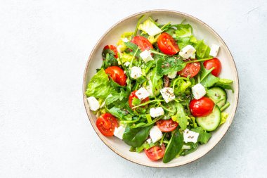 El sanatları tabağında bahar salatası. Ispanak, roka, domates ve zeytinyağlı feta. Beyaz üzerine üst görünüm.