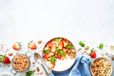 Yoğurtlu granola, fındıklı ve çilekli beyaz. Sağlıklı atıştırmalık ya da kahvaltı, meyve salatası. Kopyalama alanı olan üst görünüm.