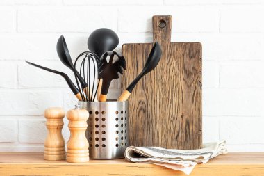 Kitchen utensils. Cooking tools with wooden cutting boards, oil and shaker at white modern kitchen interior.