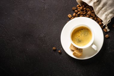 Cup of coffee espresso and bag of coffee beans at dark table . Top view with copy space.