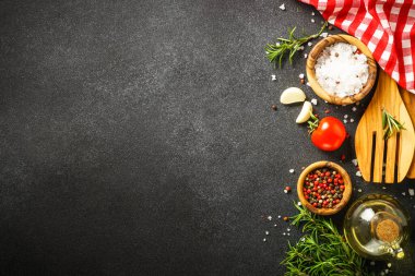 Yemek yapmak için gerekli malzemeler. Baharatlar, otlar ve mutfak aletleri. Siyah arkaplanda üst görünüm.