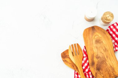 Zeytin tahtası, çatal bıçak ve masa örtüsü beyaz mutfak masasında. Kopyalama alanı olan yiyecek arkaplanı.