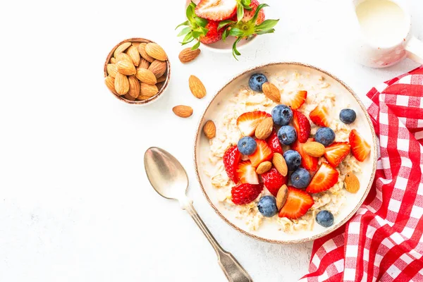 新鮮な果実とナッツを白い背景にオートミールの粥 健康的な朝食 コピースペース付きのトップビュー — ストック写真