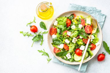 El sanatları tabağında bahar salatası. Ispanak, roka, domates ve zeytinyağlı feta. Beyaz üzerine üst görünüm.