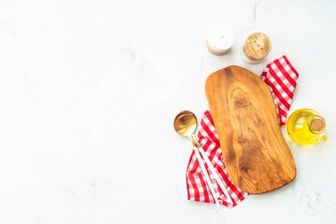 Yemek arkaplanı, beyaz mutfak aletleri. Zeytin tahtası, zeytinyağı, kaşık ve masa örtüsü. Kopyalama alanı olan düz.