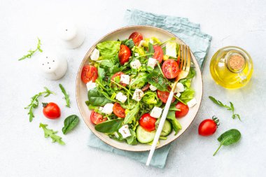 El sanatları tabağında bahar salatası. Ispanak, roka, domates ve zeytinyağlı feta. Beyaz üzerine üst görünüm.