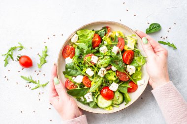 El sanatları tabağında bahar salatası. Ispanak, roka, domates ve zeytinyağlı feta. Beyaz üzerine üst görünüm.