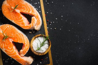 Somon balığı taze somon bifteği siyah arka planda kesme tahtasında. Kopyalama alanı olan üst görünüm.