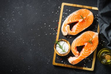 Somon balığı taze somon bifteği siyah arka planda kesme tahtasında. Kopyalama alanı olan üst görünüm.