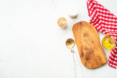 Zeytin tahtası, zeytinyağı, beyaz mutfak masasında kaşık ve masa örtüsü. Kopyalama alanı olan yiyecek arkaplanı.