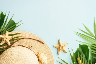 Yaz tatili ve seyahat konsepti. Palmiye yaprakları, şapka ve deniz kabukları mavi arka planda. Kopyalama alanı olan düz.