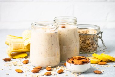 Almond banana smoothie with oat flakes in glass jars.