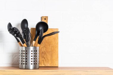Kitchen utensils. Cooking tools with wooden cutting boards, oil and shaker at white modern kitchen interior.