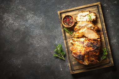 Baked ham, glazed meat with herbs on wooden cutting board. Top view on black background.