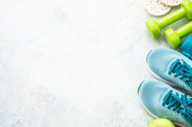 Fitness arka planı, düz görüntü. Spor ayakkabılar, dambıllar ve bir şişe su. Eğitim, egzersiz ve spor konsepti.