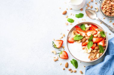 Yoğurtlu granola, fındıklı ve çilekli beyaz. Sağlıklı atıştırmalık ya da kahvaltı, meyve salatası. Kopyalama alanı olan üst görünüm.