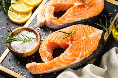 Siyah arka planda kesme tahtasında taze somon balığı bifteği. Makro.