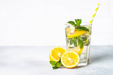 Limonata bardakta beyaz masada taze limon ve nane ile. Soğuk yaz içeceği.