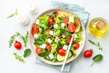 Ispanaklı yeşil salata, roka ve zeytinyağlı domates. Beyaz üzerine üst görünüm.