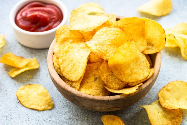 Potato chips in the bowl and ketchup sauce. Close up.